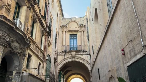 Stone archway spans narrow valletta alley ornate balcony window above weathered Видео 343676366