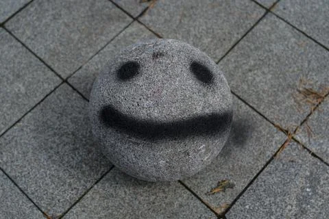 A stone ball with a face painted on it. Smiley face Stock Photos