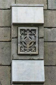 A stone bas-relief with a floral pattern, embedded in a wall. Stock Photos