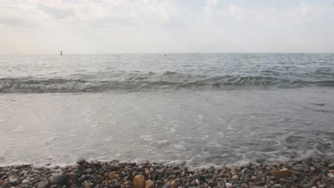 A stone beach of small pebbles washed by small foamy waves of the ocean Stock Footage 148552623