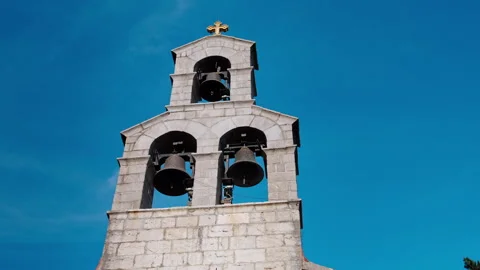 Stone bell tower with cross against blue sky Stock Footage 326970084