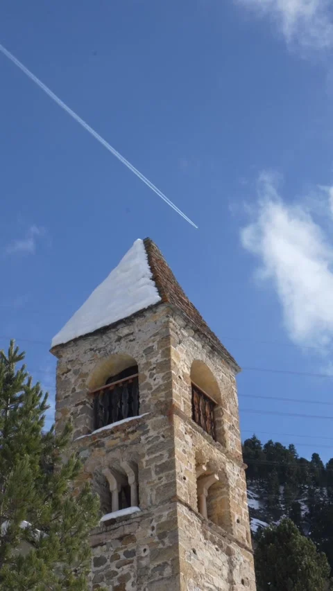 Stone bell tower with snow and airplane contrail Vidéo 329555494