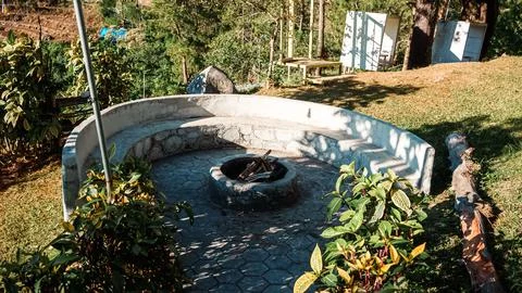 A stone bench with a fire pit in the middle of a garden Stock Photos