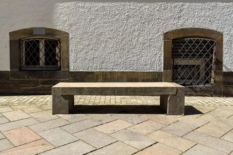 A stone bench placed between two windows in a small urban space Stockfoto's