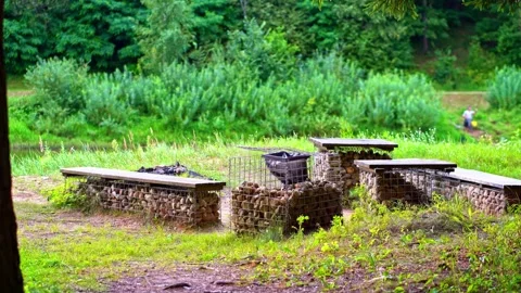 Stone benches and firepit at forest river campsite in summer daylight Stock Footage 321337072