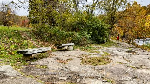 Stone Benches by Riverside Path Surrounded by Autumn Foliage Stock Photos