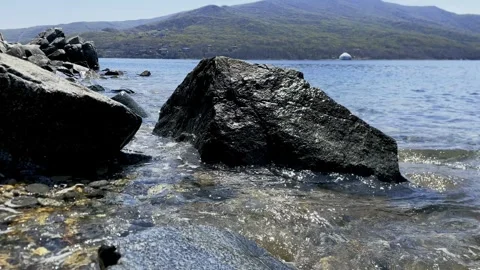 A stone block on the ocean shore is washed by waves and splashes of surf. Stock Footage 309735557