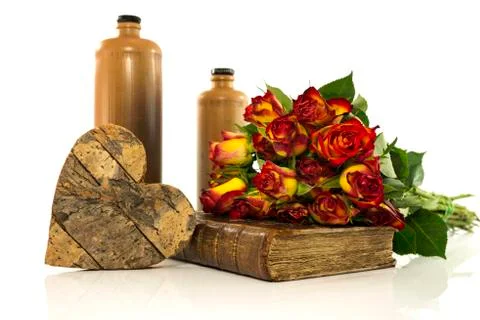 Stone bottle with old book and red roses Stock Photos