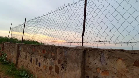 Stone Boundary Wall with Chain Link Fence Against Evening Sky Stock Footage 340560748