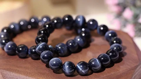 Stone bracelets display with blue tiger's eye on wooden tray Vídeo Stock 337250872