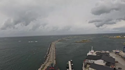 Stone breakwater jetty, small harbor lighthouse, and ocean in Andenes Norway 動画素材 342755596