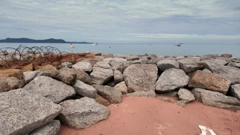 A stone breakwater leading towards a distant city skyline with boats docked in a Stock Footage 278642653