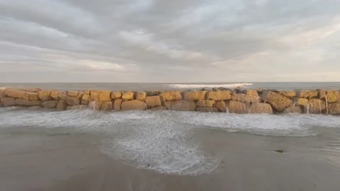 Stone breakwater on sandy seashore during storm on sunset Stock-Footage 170068412