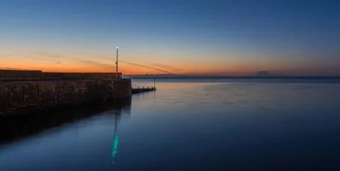 Stone breakwater at sunset Stock Photos