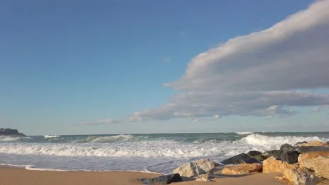 Stone breakwaters. sandy beach. blue sky. Large sea waves with white foam Stock Footage 144108484