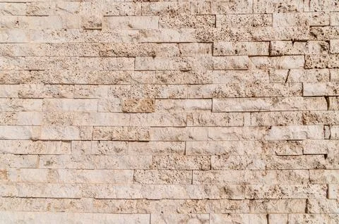 Stone brick wall displaying textured beige masonry surface Stock Photos