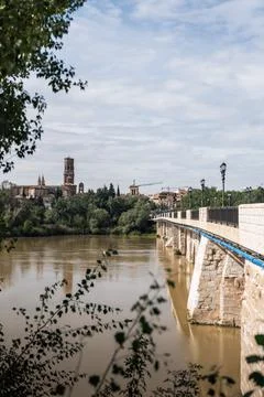 Stone bridge crossing ebro river in tudela, spain, with cathedral in background Stock Photos