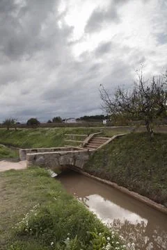 Stone bridge spanning canal with path leading up Stock Photos