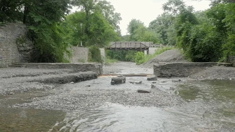 A Stone Bridge Spans a River and Rocky Stream Bed Stock Footage 81537842
