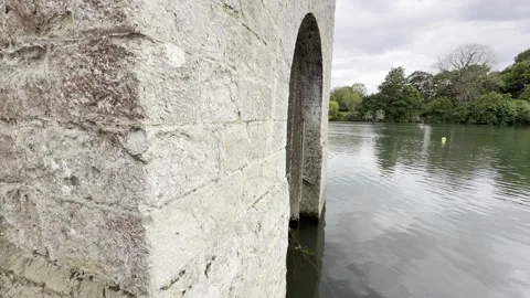 Stone building archway over calm lake panning Vídeos de archivo 334760025