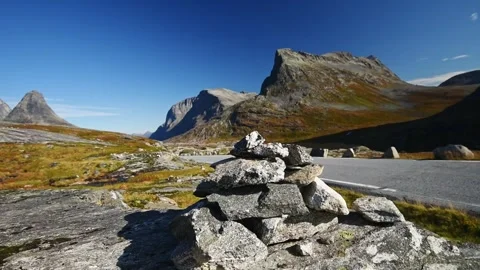 Stone cairn beside the mountain road with peaks beyond, Route 63 Trollstigen, Stock Footage 344536407