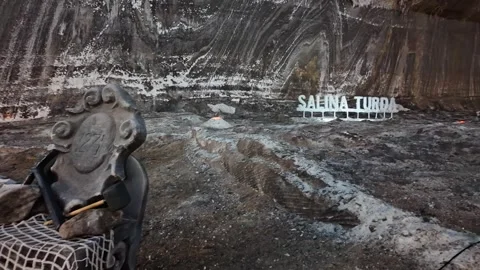 Stone chair, mining tools, and theatre inside Romania's Salina Turda salt mine Stock Footage 325764517
