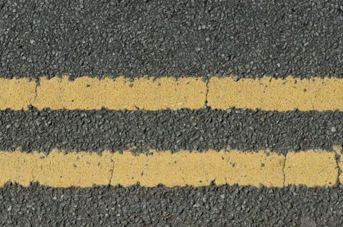 A stone chipping road surface with double yellow lines Stock Photos