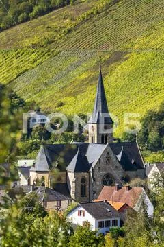 Stone church with clock tower in village valley with steep vineyard slopes in th Stock Photos