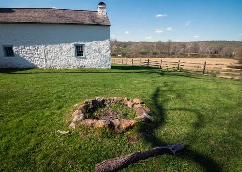 Stone circle with fire pit and idyllic rural farm cottage background Stock Photos