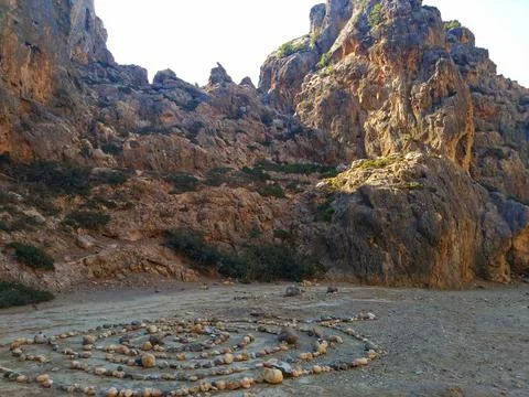 Stone circle pattern in mountain gorge, surrounded by peaks. Stock Photos