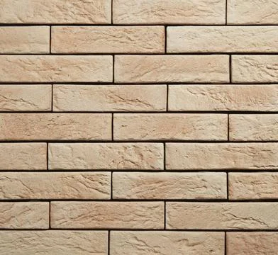 Stone cladding wall made of striped stacked slabs of yellow and brown rocks.. Stock Photos