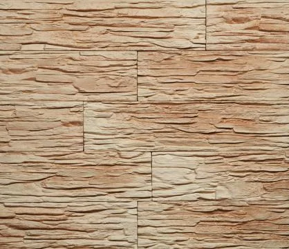 Stone cladding wall made of striped stacked slabs of yellow and brown rocks.. Stock Photos