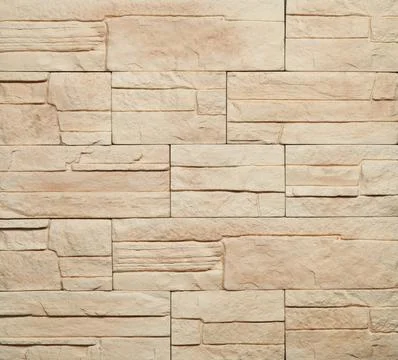 Stone cladding wall made of striped stacked slabs of yellow and brown rocks.. Stock Photos