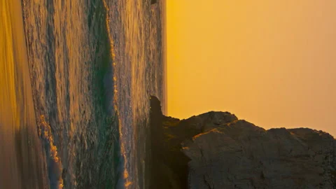 Stone cliffs sunrise beach water surface vertically oriented view. Ocean waves Stock Footage 243137527