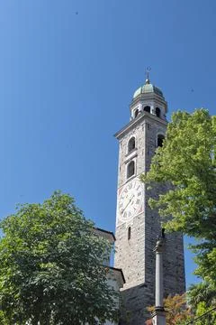 Stone Clock Tower With Green Dome And Cross Under Clear Blue Sky Surrounded.. Stock Photos