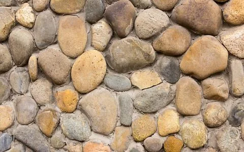 Stone cobblestone rounded gray beige pattern background part of the wall of a Stock Photos