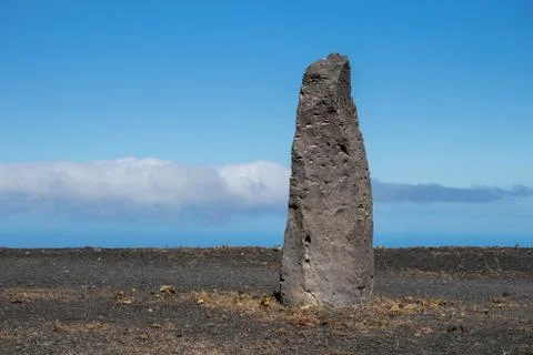 Stone column against a blue cloudy sky and ocean Stock Photos