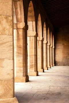 Stone columns align beautifully, casting shadows along a quiet corridor, refl Stock Photos