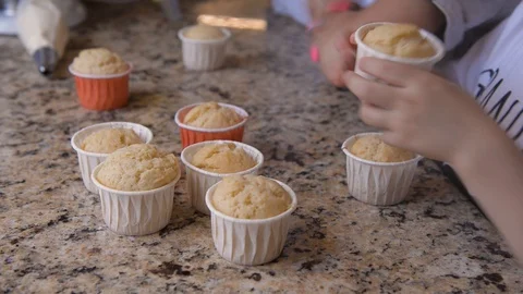 On stone countertop there are several cupcakes and childrens are trying them Stock Footage 127629249