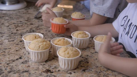On stone countertop there are several cupcakes and childrens are trying them Stock Footage 127629301