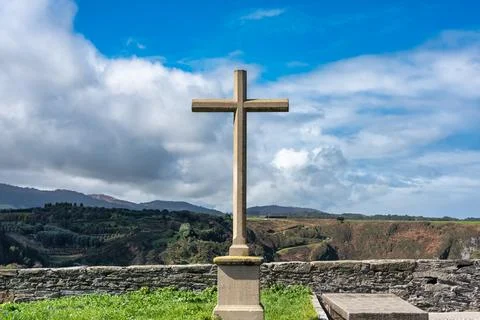Stone cross in front of the cliffs of the Cantabrian Sea in the tourist town of Stock Photos