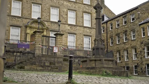 Stone cross in front of an old Victorian building in Lancaster, England Stock Footage