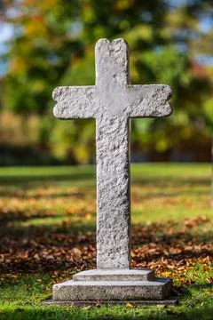 Stone cross on a graveyard in the fall. Stock Photos
