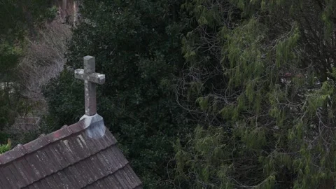 Stone cross standing on an old tiled roof surrounded by trees Stock Footage 341918599