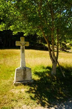 Stone crucifix under a tree Stock Photos