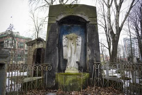 Stone crypt with headless statue of angel and metal fence 写真素材