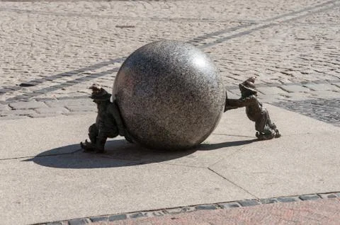 Stone dwarfs pushing the ball. Stock Photos
