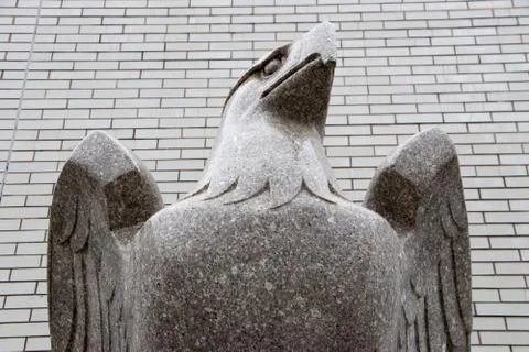 Stone Eagle Sculpture Against Brick Wall – Upward Perspective Stockfoto's