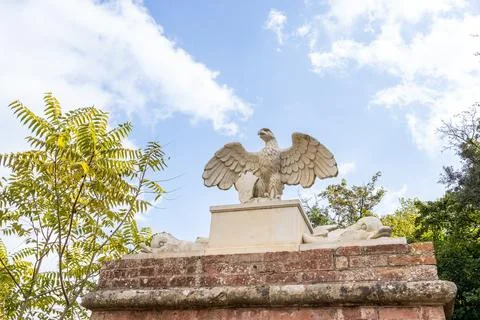 Stone eagle statue on brick monument against blue sky 스톡 사진