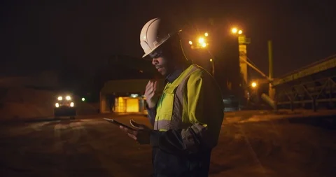 Stone extraction plant worker in safety gear using digital tablet working night Stock Footage 124303904